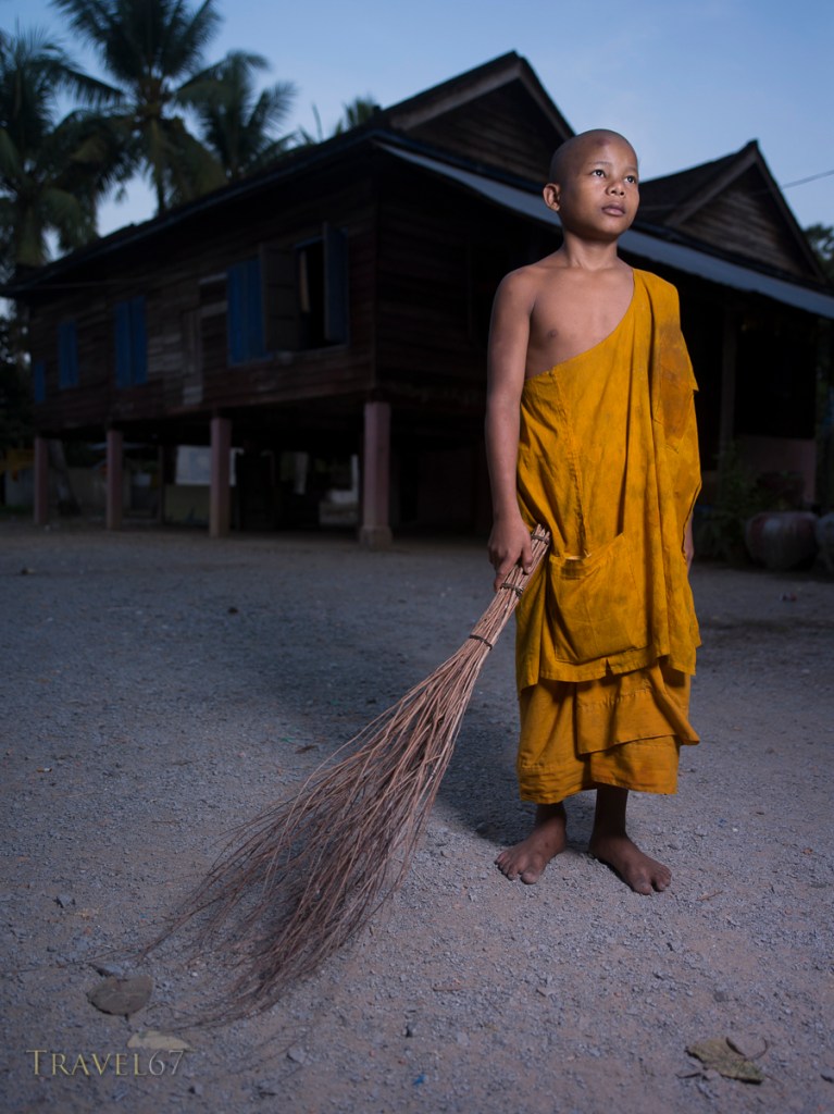 Young monk sweeping courtyard at dawn, Angkor Wat, Cambodia